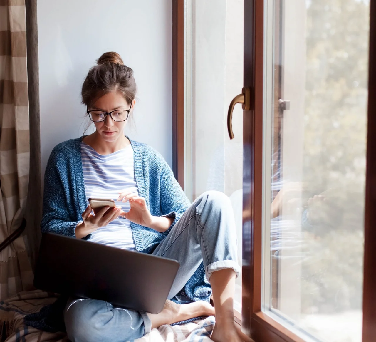 Frau mit Smartphone und Laptop