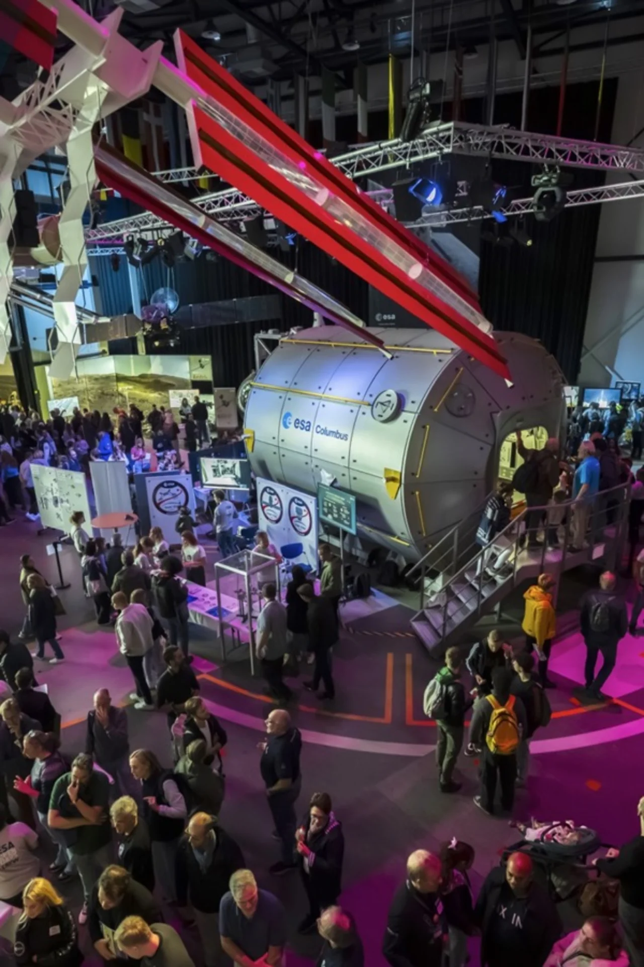 Crowd gathers around an ESA Columbus module replica at an exhibition.