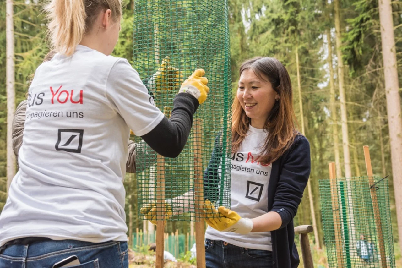 Zwei ehrenamtliche Mitarbeiterinnen pflanzen einen Baum in Deutschland