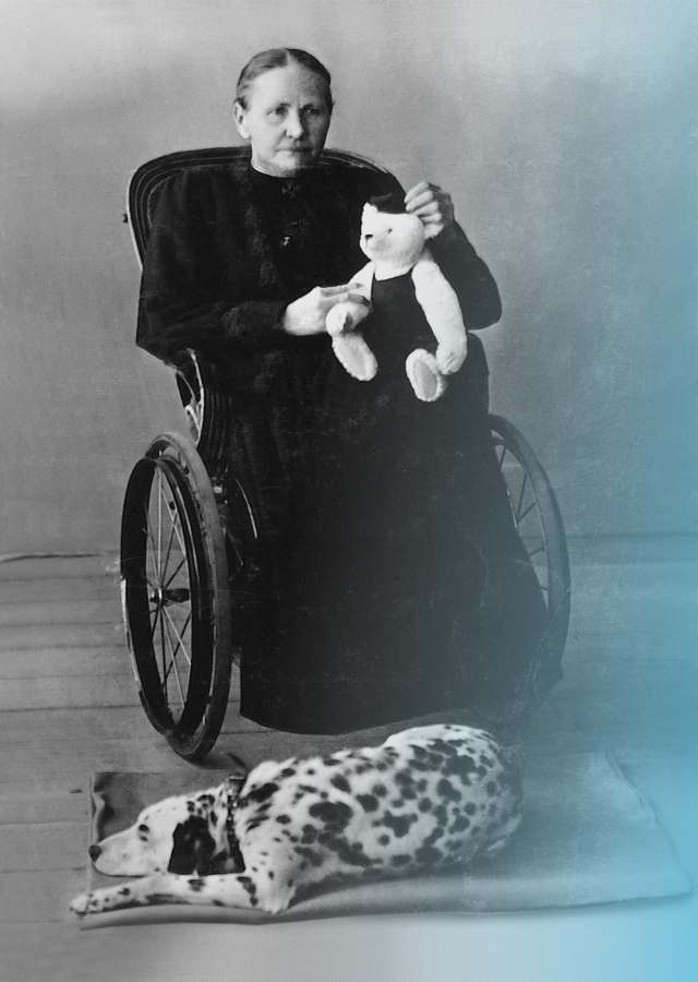 Margarete Steiff in a wheelchair with a teddy bear in her hand.